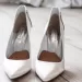 A bride's white heels on a wooden floor.