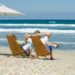 A couple sitting in chairs on the beach.