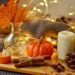 A table with warm lights and mini pumpkins.