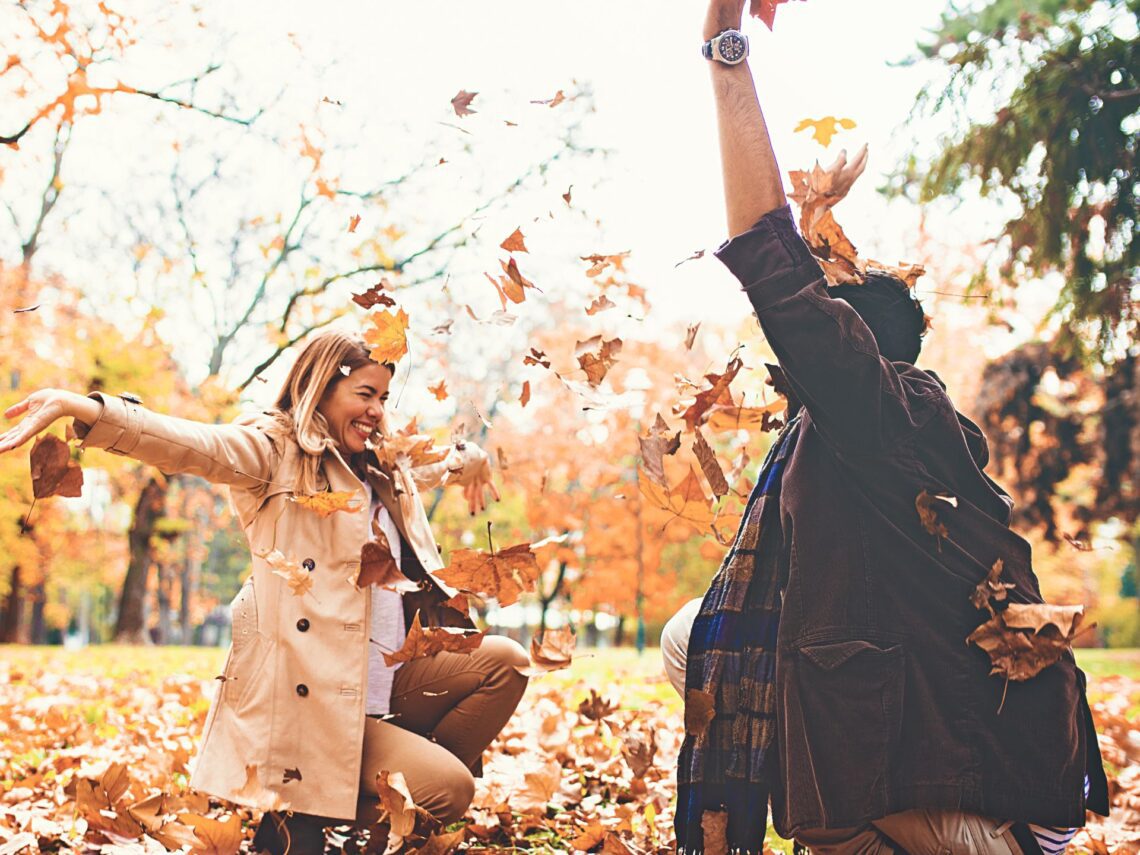 A man and women throwing leaves in the air.