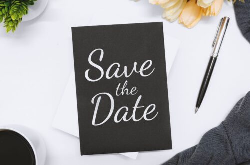 A table with a black and white colored save the date card on top.