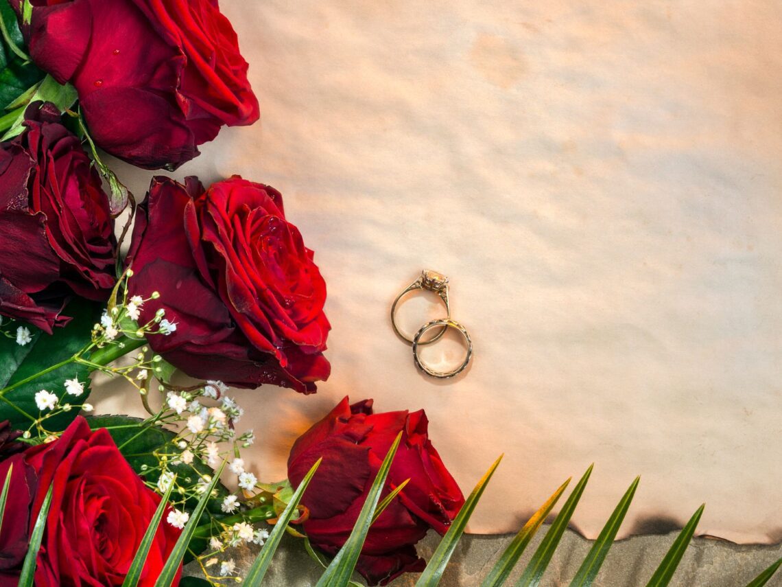 A table with red roses and gold wedding rings.