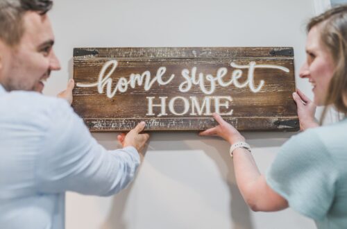 A couple putting up a home sweet home sign.