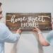 A couple putting up a home sweet home sign.