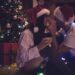 A couple kissing next to a christmas tree.