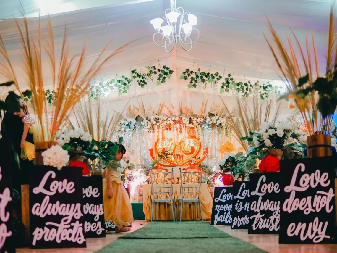 A wedding aisle decorated with black love signs and green leaves.