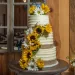 A rustic wedding cake decorated with sunflowers.