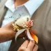A woman putting on the groom's wedding boutonniere.