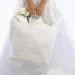 A bride carrying a white gift bag filled with gifts.