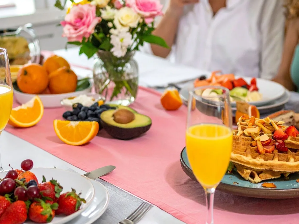 A group of girls around a table packed with brunch items.